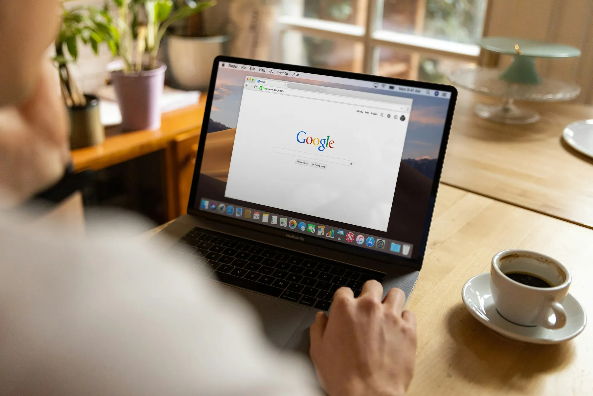 Laptop z otwartą stroną wyszukiwarki Google na drewnianym stole obok filiżanki kawy